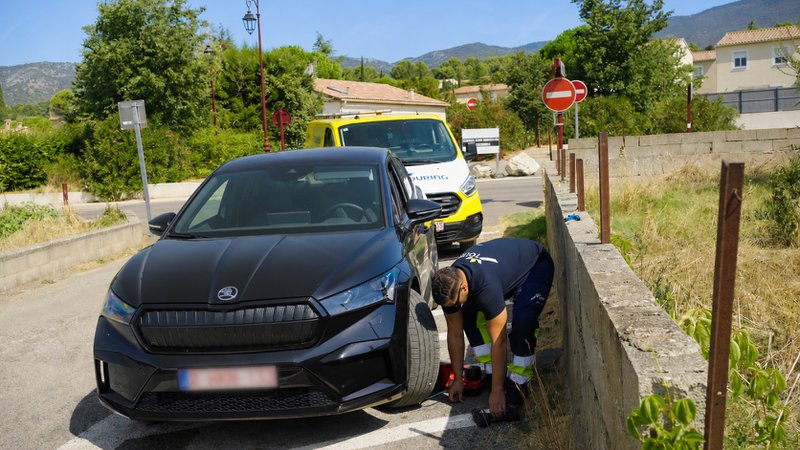 Un dépanneur répare une voiture sur le bord d'une route de campagne.