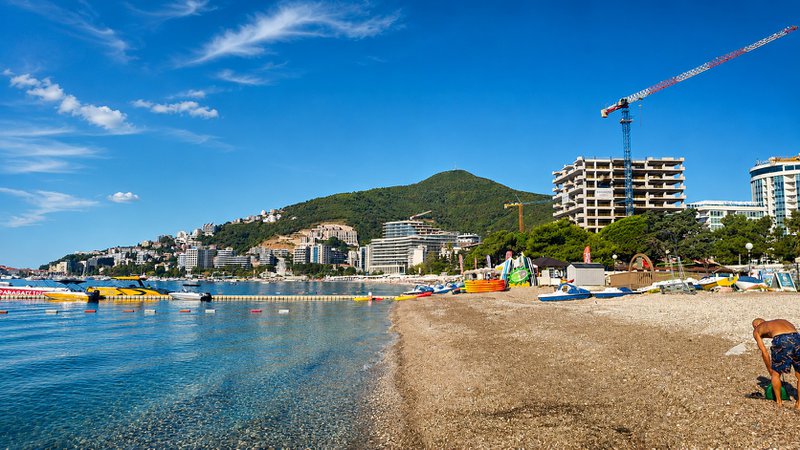 la mer, la plage et un immeuble en construction avec une grue au Monténégro.