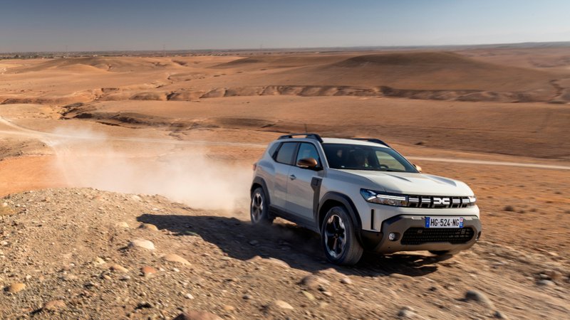 Dacia Duster rijdt over een woestijnweg, compacte SUV in actie op stoffig terrein