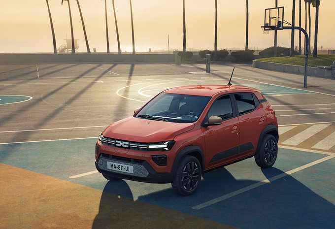 Dacia Spring rouge sur un terrain de basket au coucher du soleil.