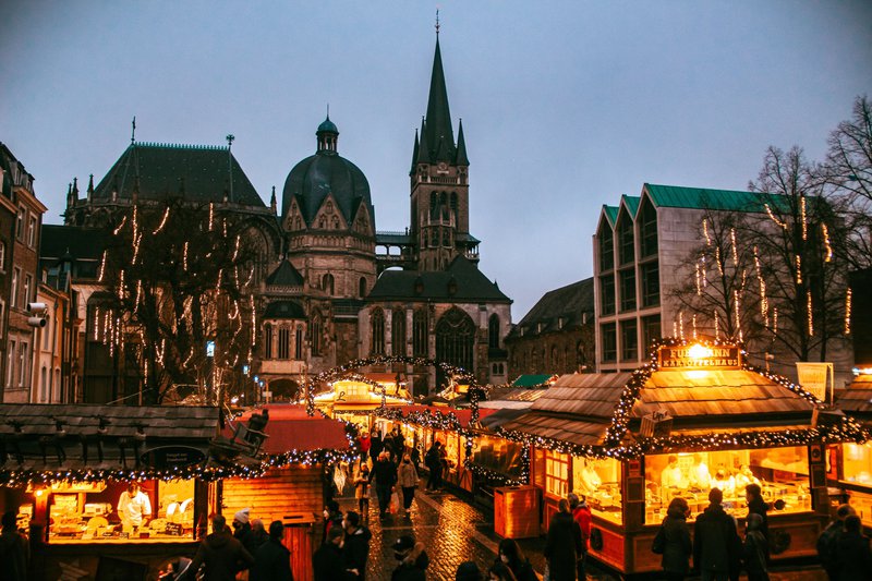 Stands de Noël illuminés la nuit, avec la cathédrale d'Aix-la-Chapelle en arrière-plan.