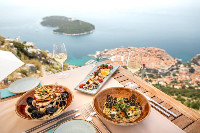 twee borden met heerlijk eten op een terras met bovenaanzicht op Dubrovnik in Kroatië