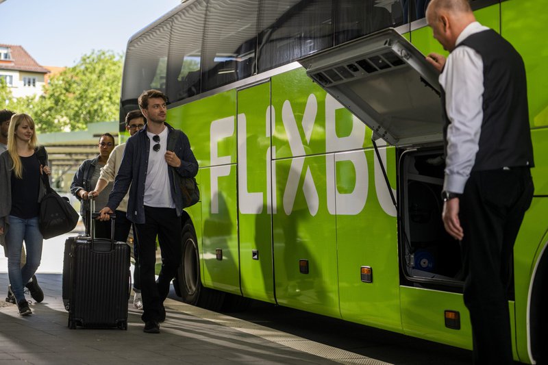 Groene autocar en mensen met bagage, klaar voor vetrek naar Aken.