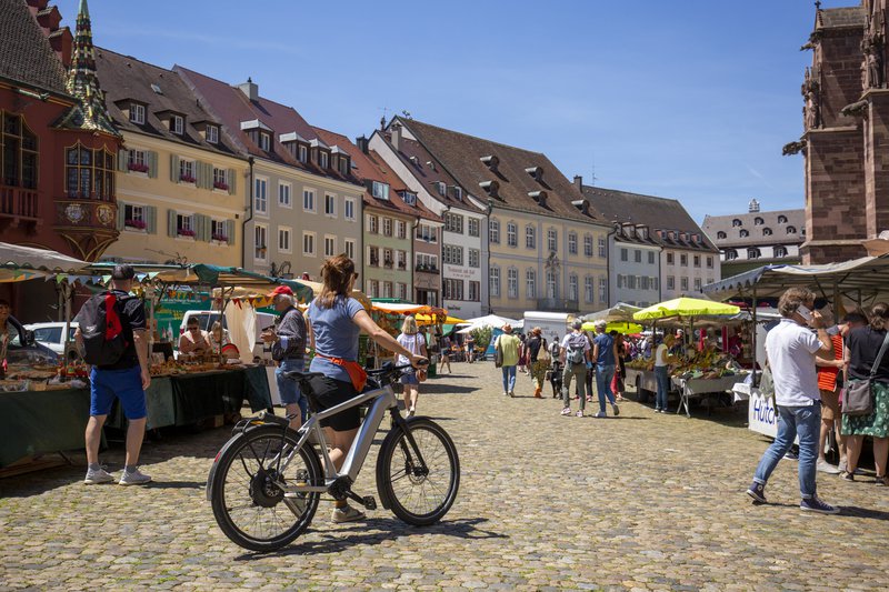 E-bike op een marktplein in Freiburg met kraampje en veelkleurige gevels.