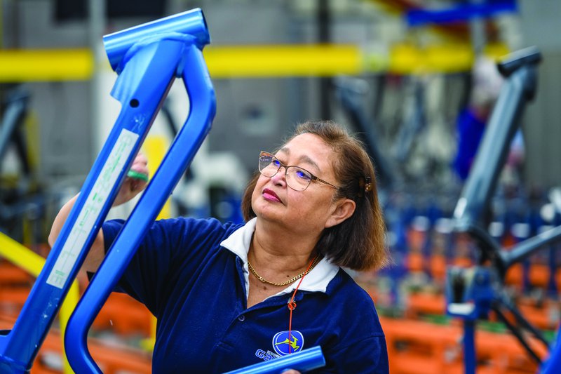 vrouw in blauwe overal werkt aan een elektrische fiets