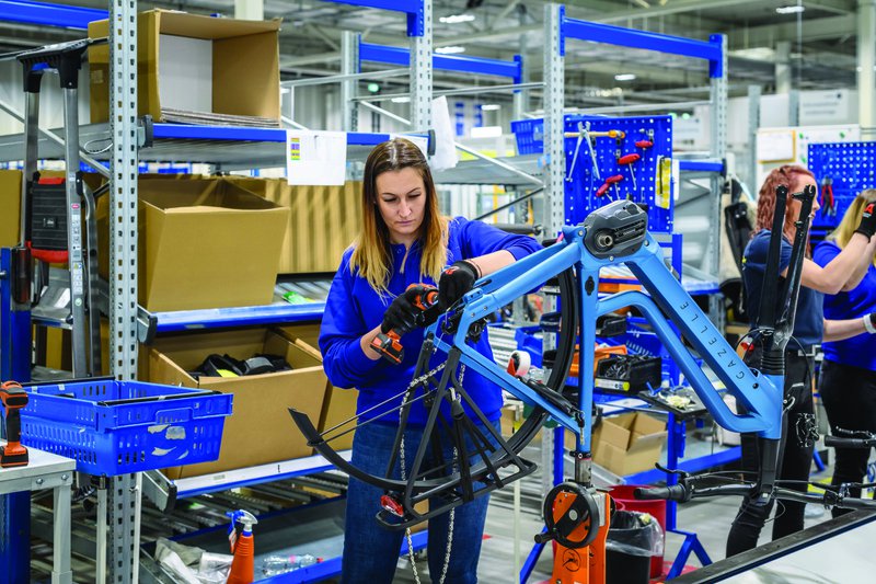 vrouw in blauwe overal werkt aan een elektrische fiets van het merk Gazelle