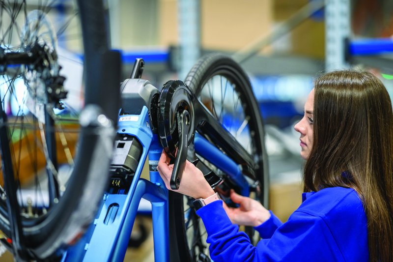 vrouw in blauwe overal werkt aan een elektrische fiets