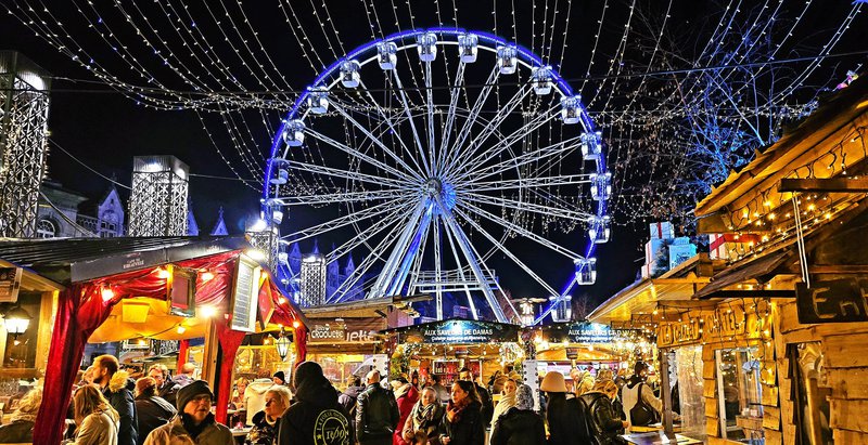 kerstkraampjes bij nacht met verlicht reuzenrad op de achtergrond