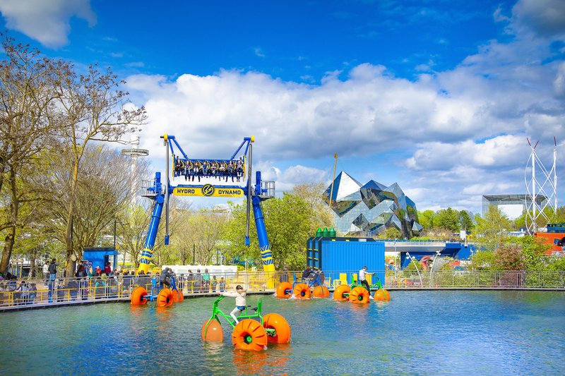 Pédalos sur l'eau et bâtiments modernes en arrière-plan sous un ciel bleu au Futuroscope de Poitiers.