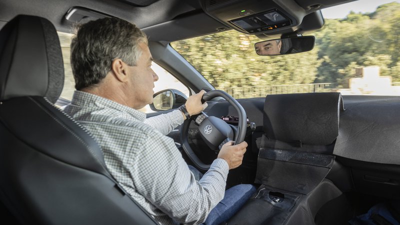 Conducteur au volant du prototype camouflé de la future Volkswagen ID.Polo, avec planche de bord partiellement dissimulée.