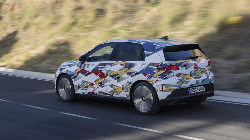 Prototype camouflé de la Volkswagen ID.Polo vu de trois quarts arrière, en mouvement sur route.