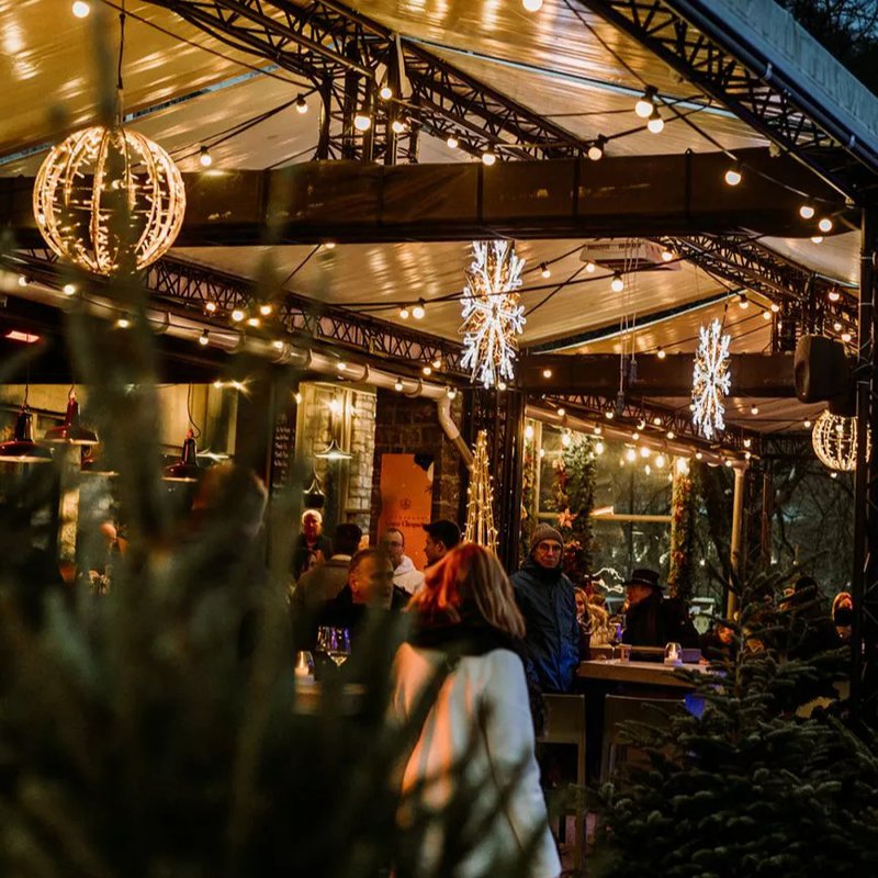 Chalet de Noël convivial avec illuminations festives et personnes habillées chaudement.