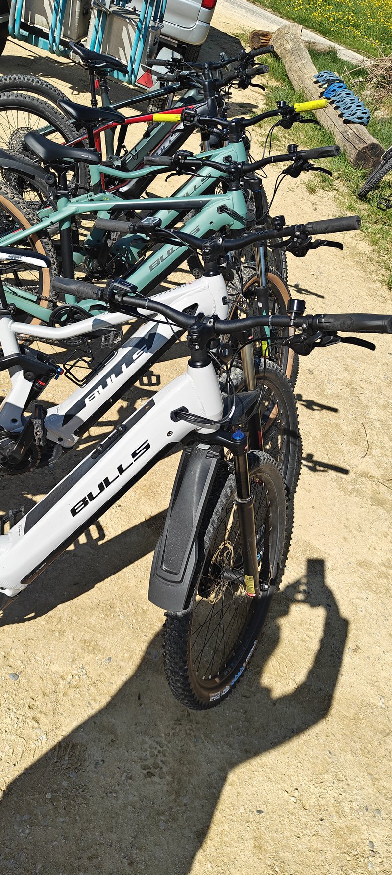 Plusieurs vélos électriques rangés à l'extérieur au soleil l'un à côté de l'autre.