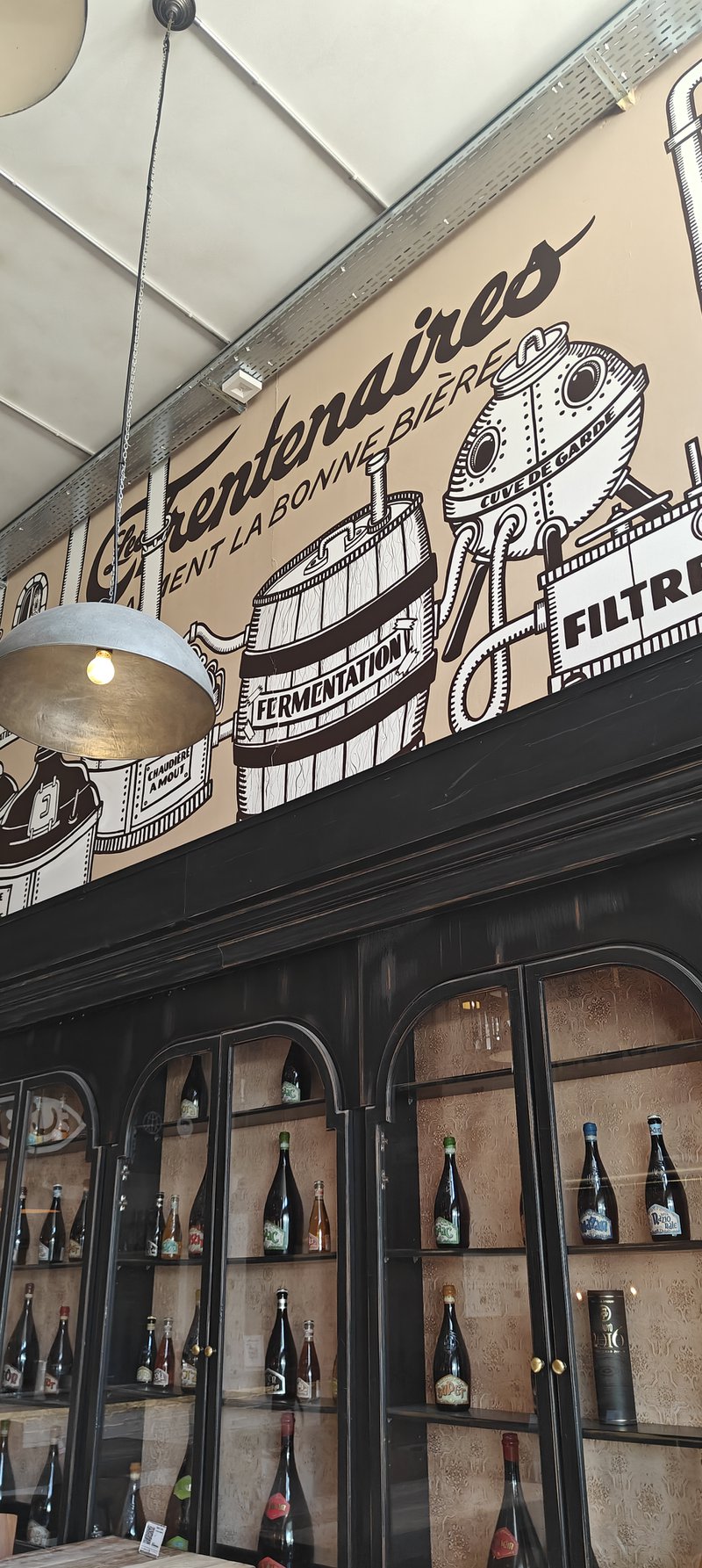 Intérieur d'un restaurant-brasserie, vitrines en bois avec des bouteilles de bières.