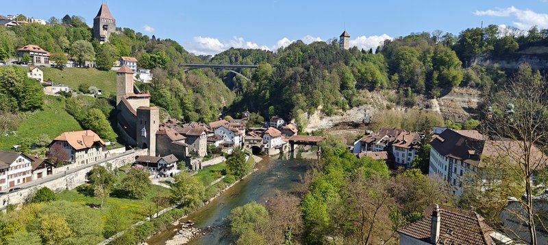 Village en Suisse traversé par un cours d'eau sur fond de ciel bleu.