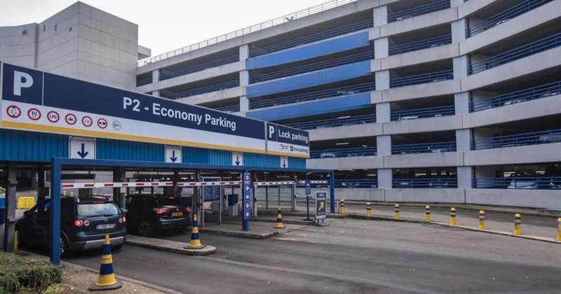 Parking à l'aéroport - l'entrée avec deux voitures et le parking en arrière-plan