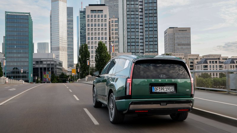 Hyundai Ioniq 9 en circulation en ville, avec skyline moderne en arrière-plan.
