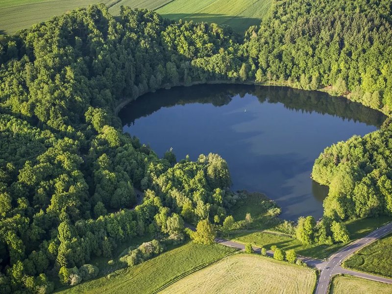 met water gevulde krater omzoomd door bomen - routes Europa