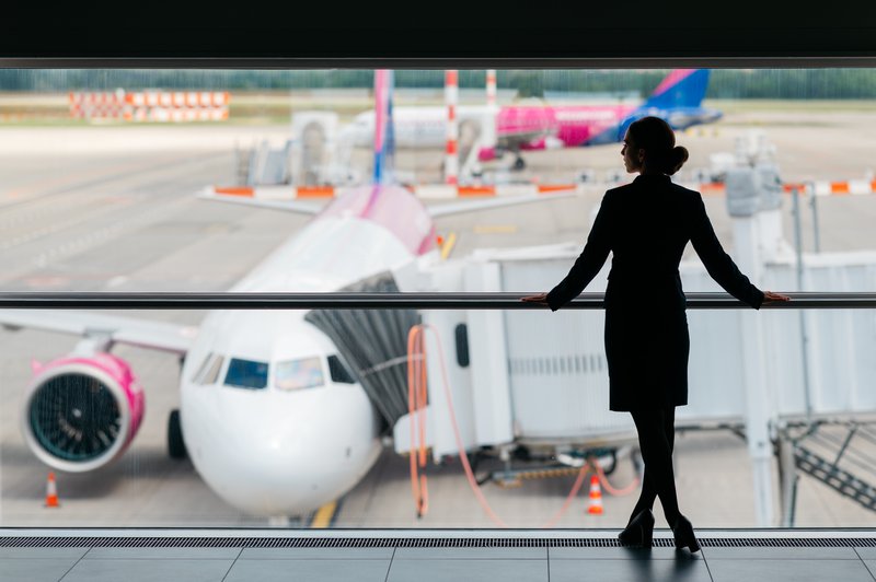 Hôtesse de l'air à l'aéroport de Budapest avec deux avions en arrière-plan.