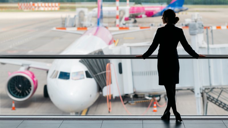airhostess op luchthaven met op achtergrond twee vliegtuigen op het tarmac