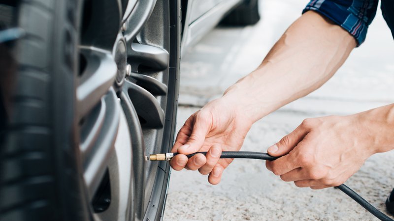 Un homme vérifie la pression des pneus de sa voiture juste avant de reprendre la route
