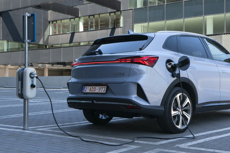 Achteraanzicht van een elektrische auto, aangesloten aan een oplader.