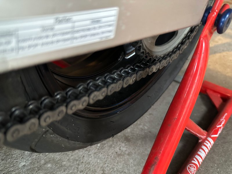 Chaîne moto et pignon sur béquille de paddock pour contrôle de tension et d'usure.