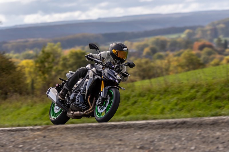 Kawasaki Z1100 en action sur une route de campagne, collines en arrière-plan