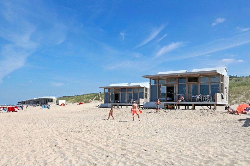 kinderen spelen op een strand in de nabijheid van strandhuisjes