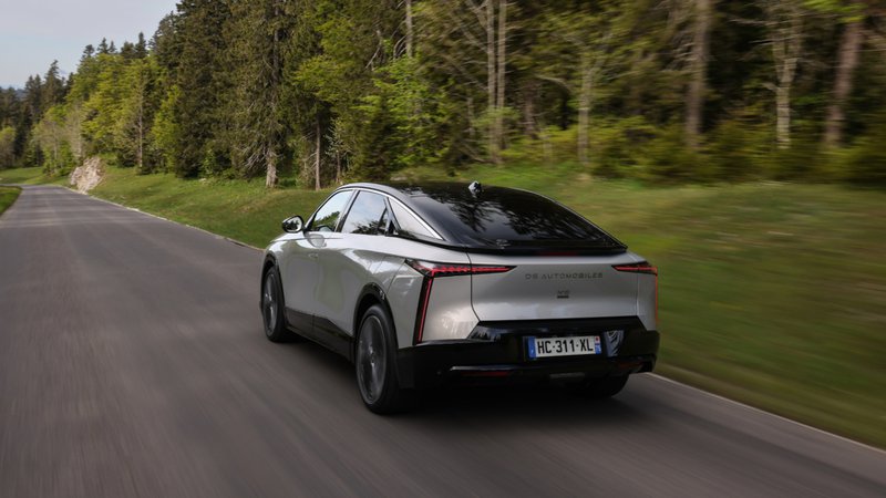 DS 8 vu de l’arrière sur route forestière, avec design élancé et feux LED distinctifs.
