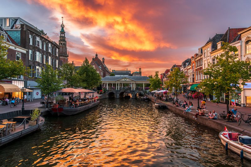 Un canal bordé de terrasses dans une ville au coucher du soleil.