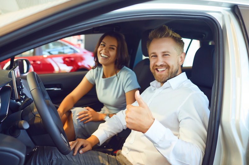 Tweedehands: klanten die hun auto gaan testen, bestuurder met de duim omhoog.