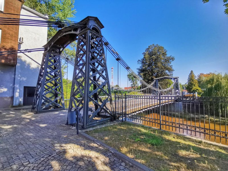 Pologne, passerelle suspendue au-dessus d'une rivière, ciel bleu.