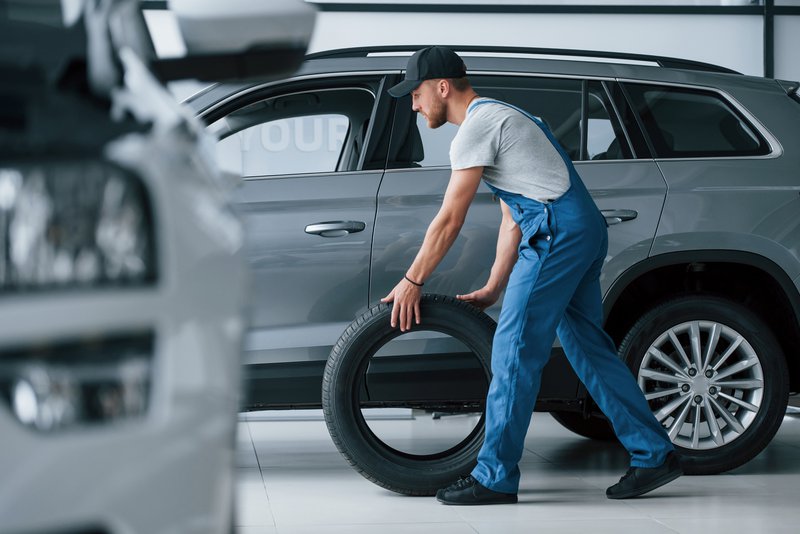 Tweedehands: een monteur laat een band voor een SUV rollen in een garage.