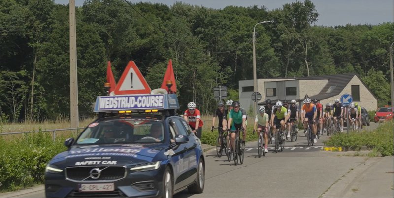 Peleton van fietsers met begeleiding