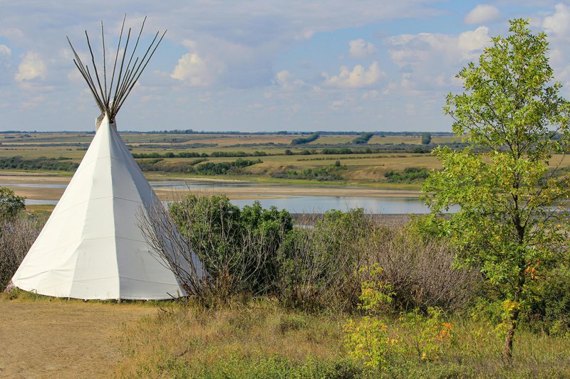 tipi in het groen nabjj een rivier met groene oevers