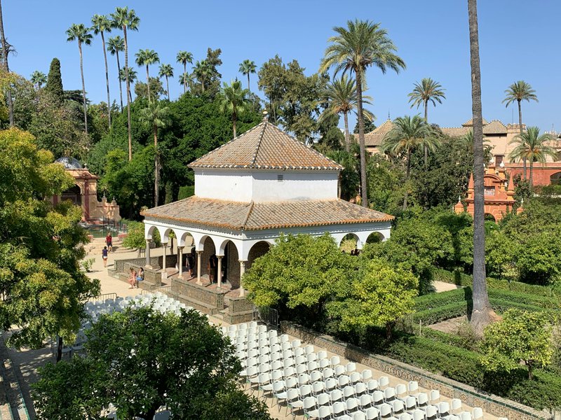 Bâtiment carré blanc avec toit pointu carré dans un parc avec des palmiers.