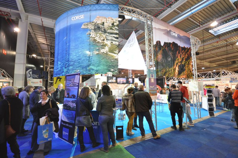 Mensen op een beurs bij een hoge stand van een exposant.