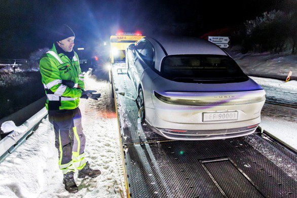Une voiture Lucid Air est remorquée sur un camion dans un paysage enneigé