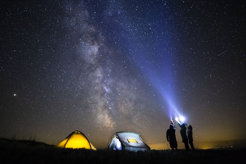 Deux tentes éclairées la nuit sous un ciel étoilé.