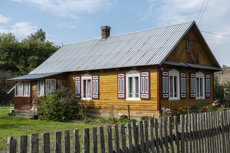 Maison en bois dans la nature avec un toit en tôle et un petit jardin.