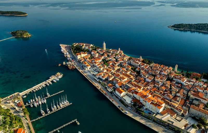 luchtfoto van eiland Rab (Kroatië) met honderden witte huizen blakend in de avondzon