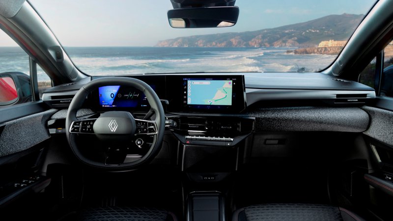 Habitacle de la Renault Clio avec instrumentation numérique, écran central et vue sur la mer à travers le pare-brise.