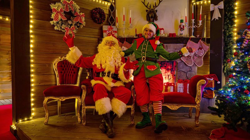 kerstman en hulpje gezellig in een kerstdecor