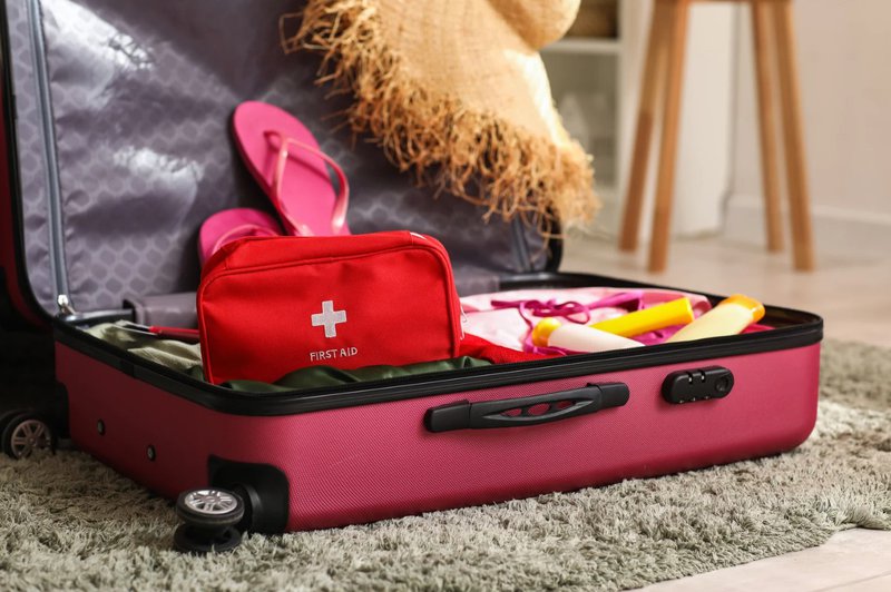 Un bagage à main rose avec une trousse de premiers secours.