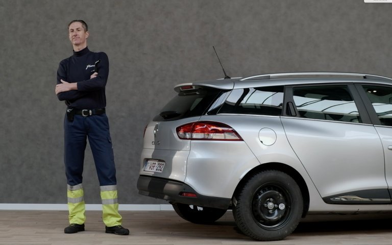 man naast een grijze auto met een reserve band gemonteerd
