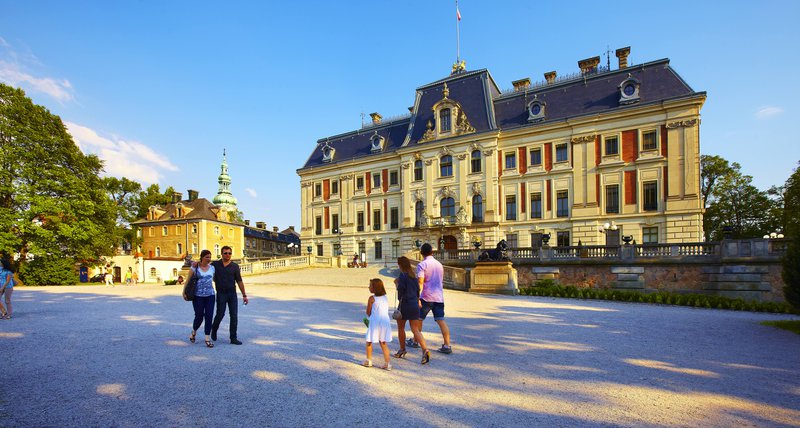 Pologne, château à la façade rouge et beige, visiteurs sur la place devant.