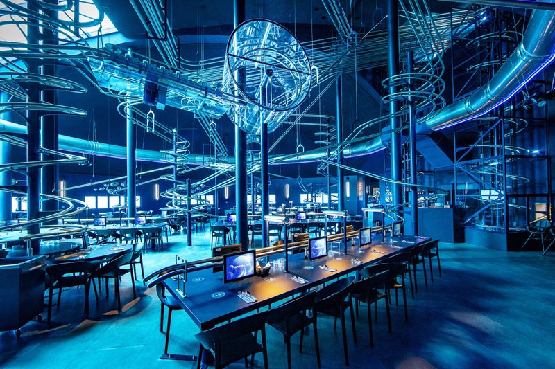 Restaurant futuriste avec des montagnes russes qui apportent les plats aux tables.