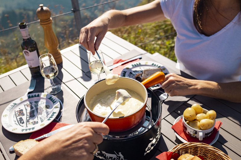Deux femmes dégustent une fondue au Moléson dehors au soleil.