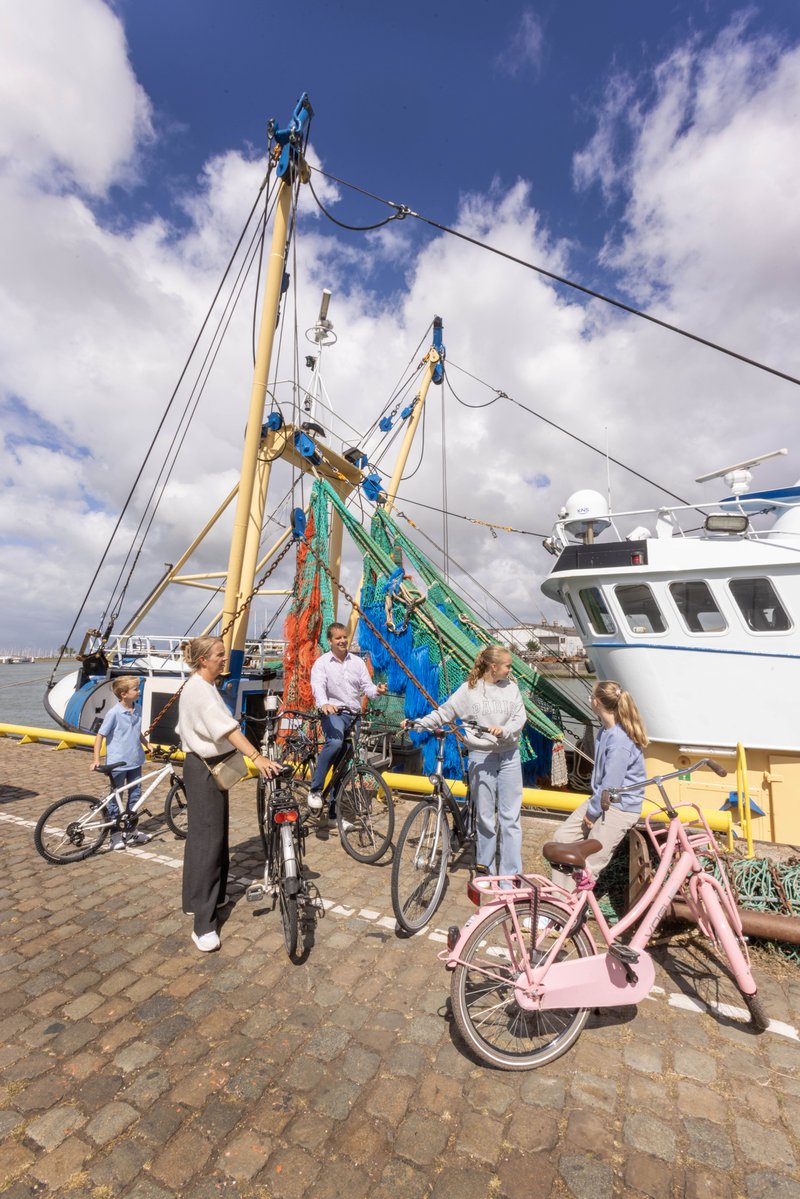 Fietsers nabij een vissersboot aan kade